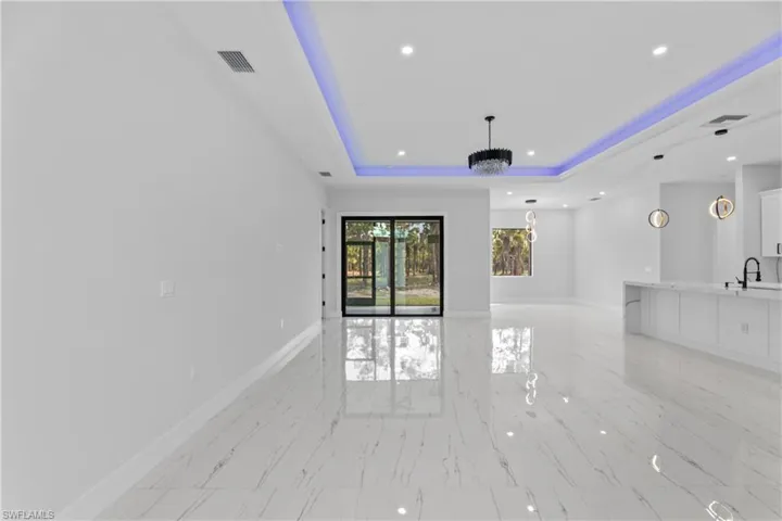 Unfurnished living room with recessed lighting, a raised ceiling, visible vents, and baseboards