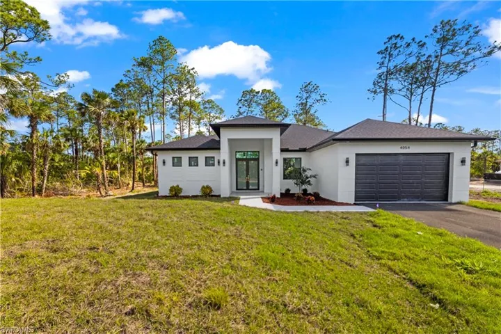 View of front of house featuring aphalt driveway, stucco siding, an attached garage, and a front yard