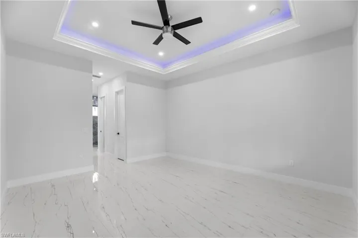 Empty room with ceiling fan, a tray ceiling, recessed lighting, and baseboards