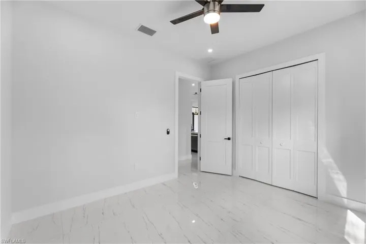 Unfurnished bedroom featuring marble finish floor, baseboards, visible vents, and a closet