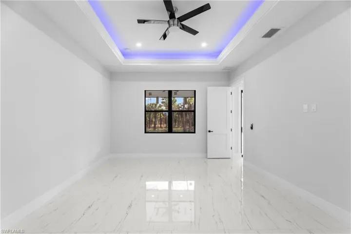 Spare room with marble finish floor, a raised ceiling, visible vents, and baseboards