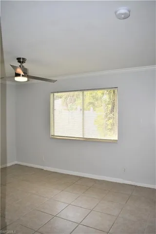 Empty room with a ceiling fan, crown molding, baseboards, and a healthy amount of sunlight