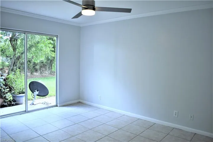 Spare room with a ceiling fan, light tile patterned flooring, ornamental molding, and baseboards