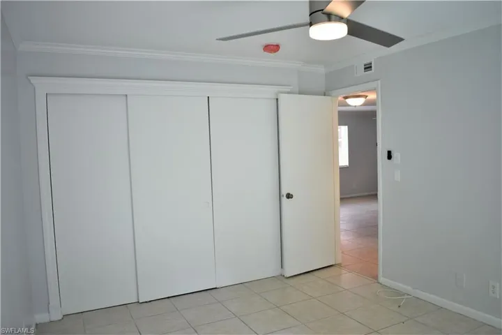 Unfurnished bedroom with crown molding, a closet, ceiling fan, and visible vents