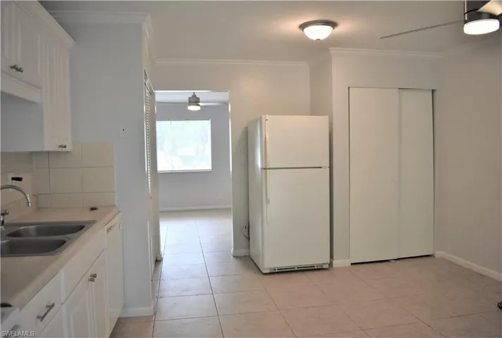 Kitchen with white appliances, ornamental molding, decorative backsplash, a sink, and ceiling fan