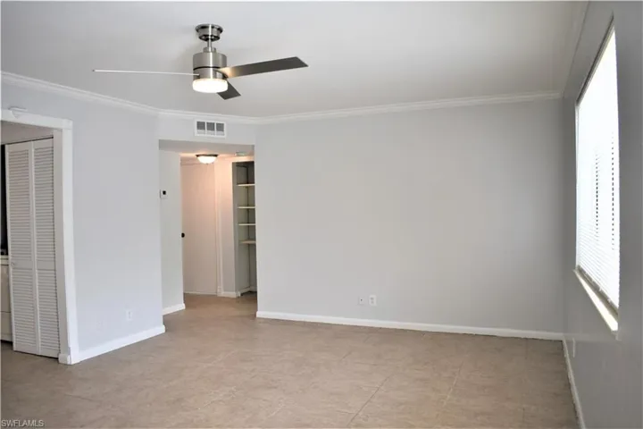 Unfurnished room with baseboards, ornamental molding, visible vents, and a ceiling fan