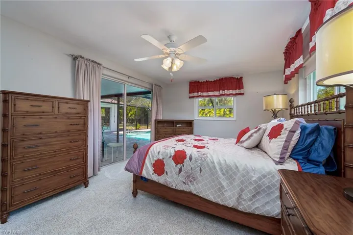 Owners' bedroom with sliders to the pool, walk in closet, light carpet & a ceiling fan.