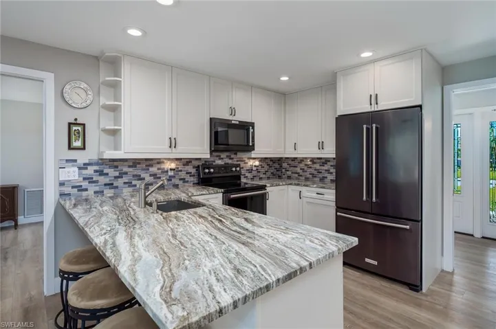 Kitchen with newer stainless-steel appliances and large breakfast bar.