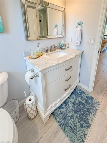 Bathroom with baseboards, toilet, wood finished floors, and vanity