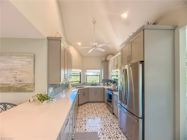 Kitchen with a ceiling fan, a sink, stainless steel appliances, light tile patterned flooring, and light countertops