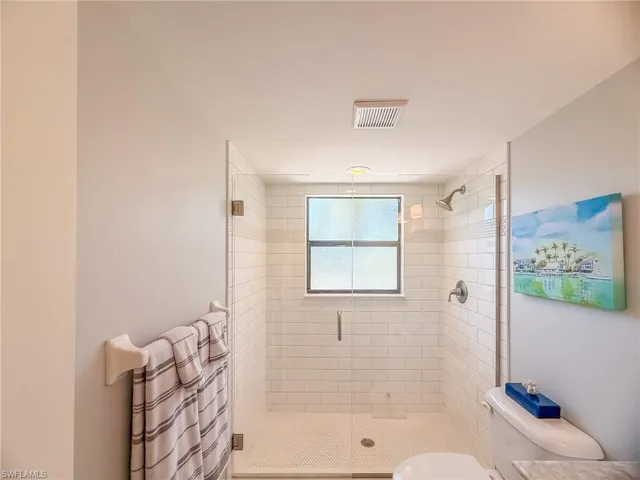 Full bathroom with toilet, visible vents, and a stall shower