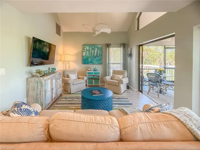 Living room featuring vaulted ceiling, wood finished floors, visible vents, and baseboards