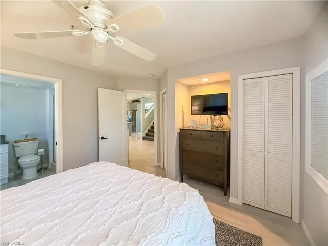 Bedroom featuring baseboards, multiple closets, a ceiling fan, and ensuite bathroom