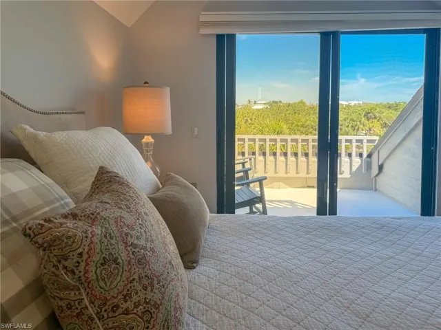 Bedroom with multiple windows, lofted ceiling, and access to exterior
