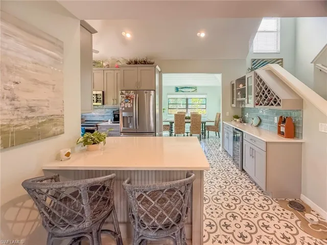 Kitchen with a peninsula, stainless steel appliances, light countertops, a kitchen breakfast bar, and backsplash
