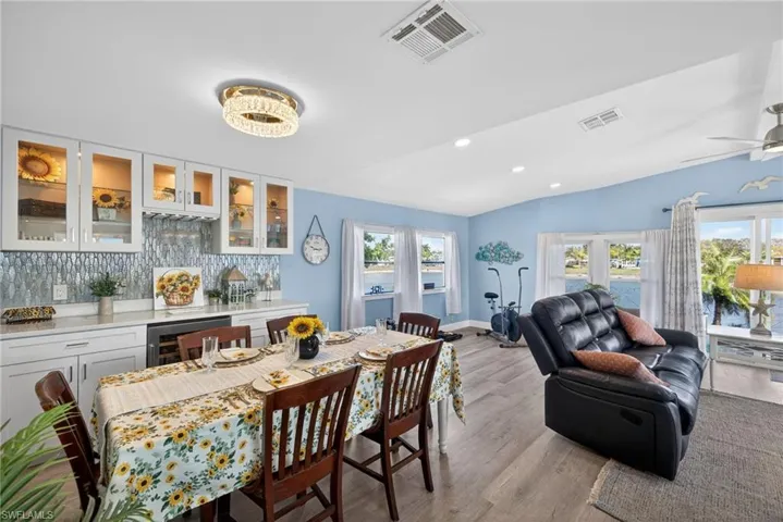 Dining space with light wood finished floors, wine cooler, vaulted ceiling, recessed lighting, and a ceiling fan