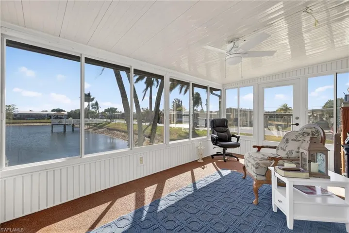 Sunroom / solarium with a ceiling fan and a water view