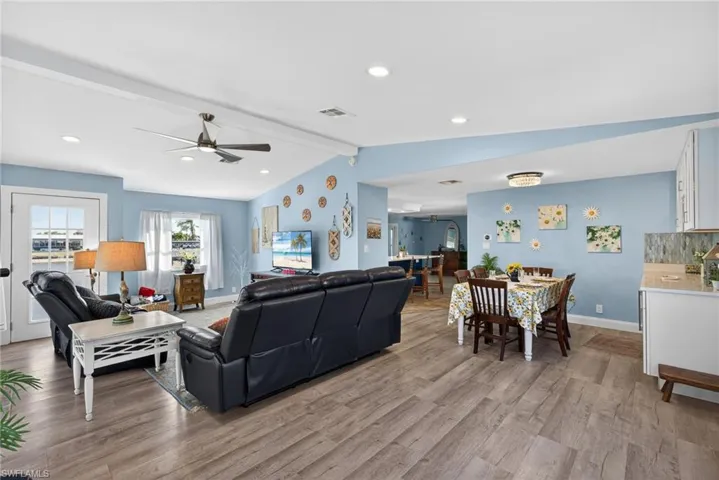 Living room with ceiling fan, light wood-style floors, beam ceiling, and recessed lighting