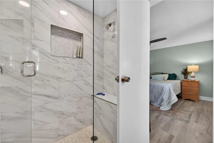 Full bath with ensuite bathroom, a shower stall, and light wood finished floors