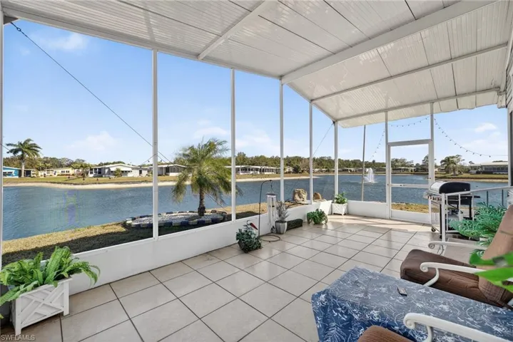 Sunroom / solarium with floor to ceiling windows, tile patterned floors, a water view, and vaulted ceiling
