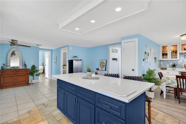 Kitchen featuring blue cabinetry, a breakfast bar, light stone countertops, a kitchen island, and recessed lighting