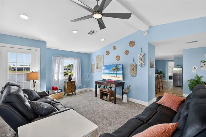 Living area featuring a ceiling fan, vaulted ceiling with beams, carpet flooring, and recessed lighting