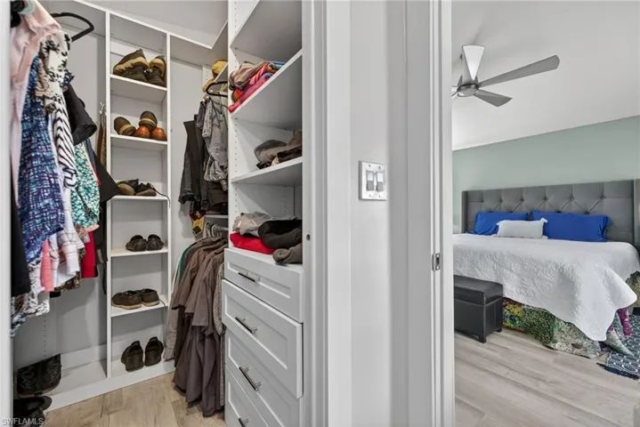 Walk in closet with light wood-style floors and ceiling fan