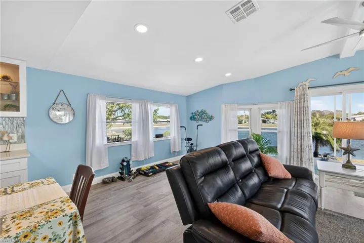 Living area featuring lofted ceiling, a ceiling fan, wood finished floors, and recessed lighting