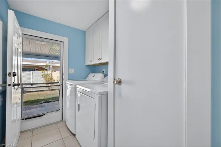 Laundry area featuring cabinet space, light tile patterned floors, and separate washer and dryer