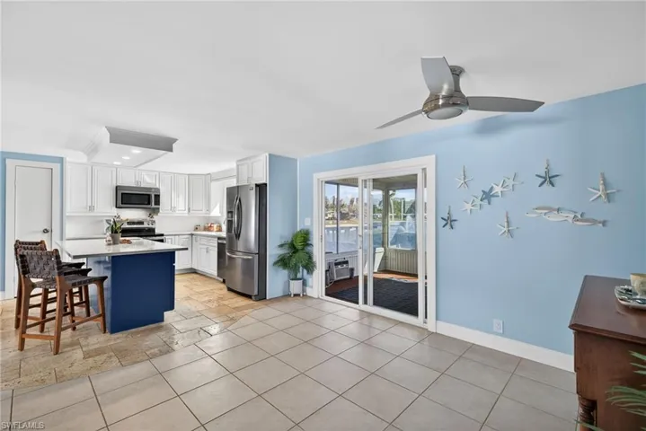 Kitchen featuring stainless steel appliances, ceiling fan, a breakfast bar area, a kitchen island, and light stone counters