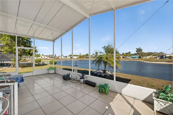 Unfurnished sunroom featuring a residential view, a water view, and lofted ceiling