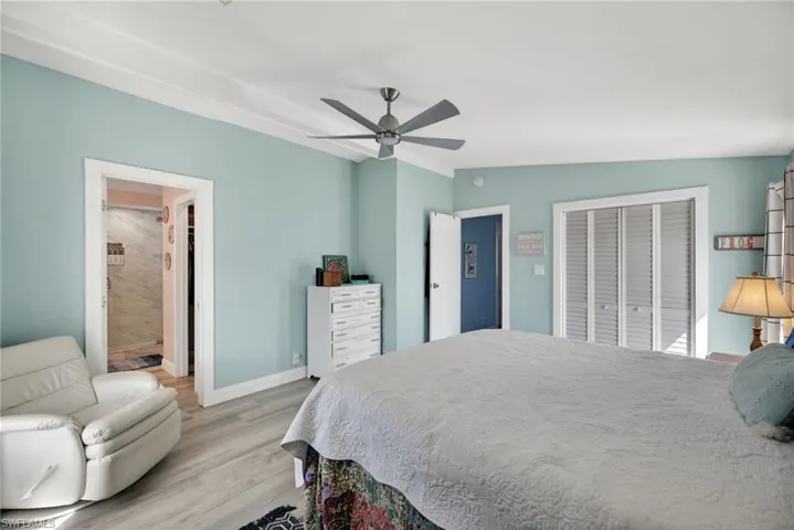 Bedroom with ceiling fan, light wood-style flooring, a closet, vaulted ceiling, and ensuite bath