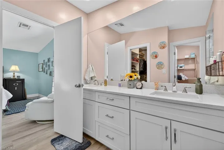Full bathroom featuring double vanity, light wood-type flooring, and a spacious closet