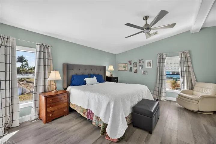 Bedroom featuring wood finished floors, a ceiling fan, and vaulted ceiling with beams