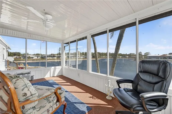 Sunroom with a ceiling fan, carpet, and a water view