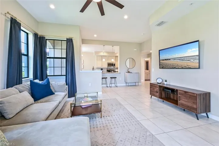 Living room with light tile patterned floors, ceiling fan, and recessed lighting