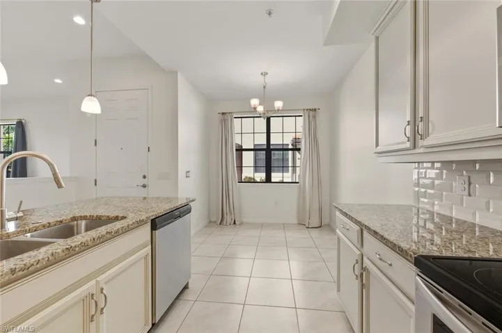 Kitchen featuring light stone countertops, dishwasher, pendant lighting, light tile patterned flooring, and a chandelier