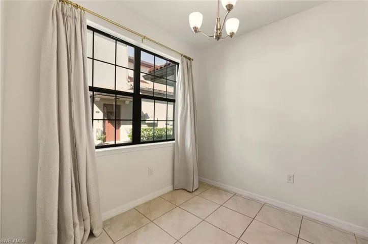 Unfurnished room featuring a chandelier and light tile patterned floors