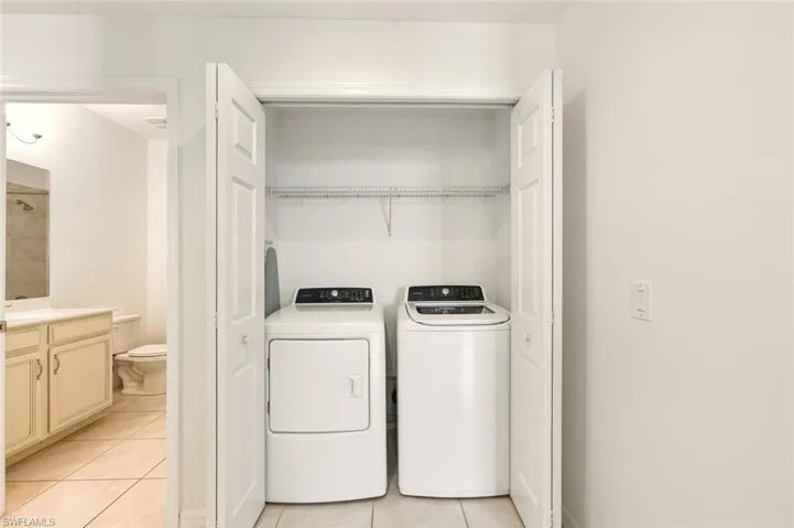 Washroom with light tile patterned flooring and washer and dryer
