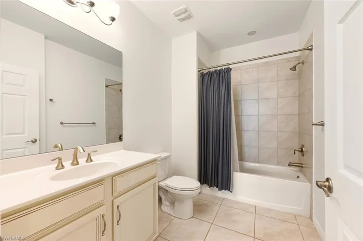 Full bath with vanity, shower / bathtub combination with curtain, and light tile patterned floors