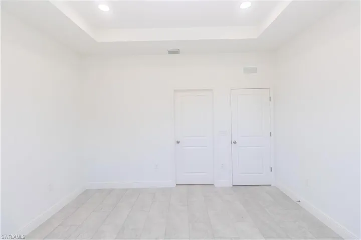 Unfurnished bedroom featuring a raised ceiling and recessed lighting