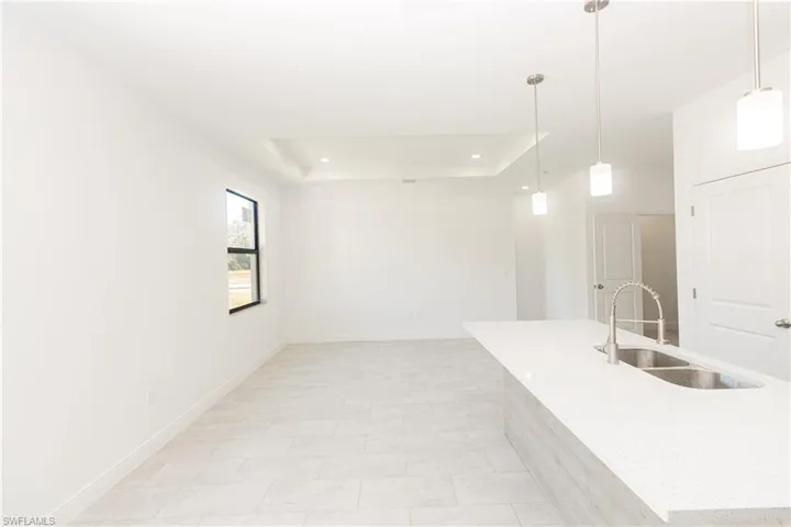 Kitchen with hanging light fixtures, a tray ceiling, and light stone countertops