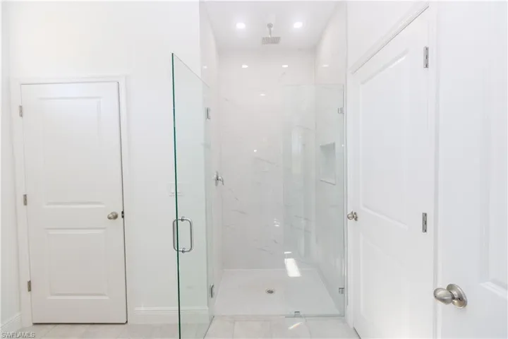 Bathroom featuring a marble finish shower, recessed lighting, and tile patterned flooring