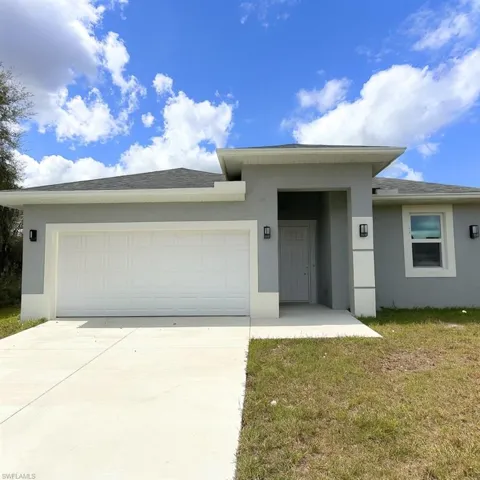 View of front of house with stucco siding, concrete driveway, a garage, a front lawn, and roof with shingles