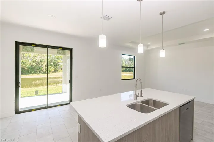 Kitchen featuring light stone counters, pendant lighting, dishwasher, light brown cabinets, and recessed lighting