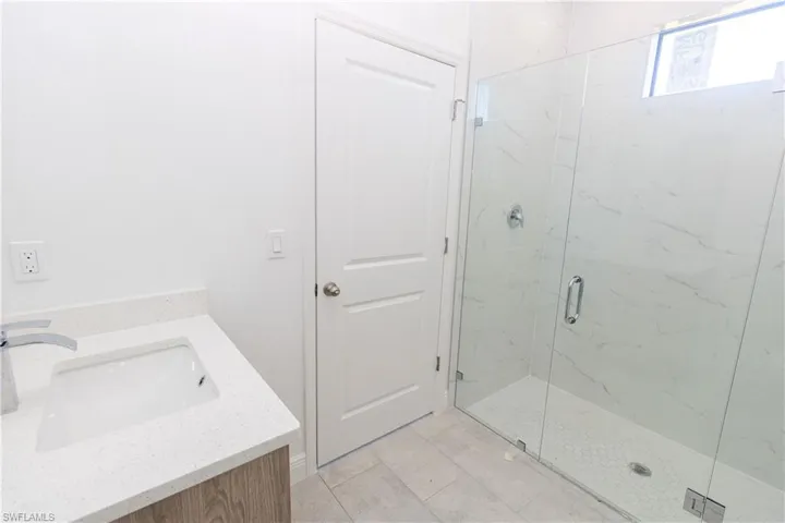Bathroom with vanity and a marble finish shower