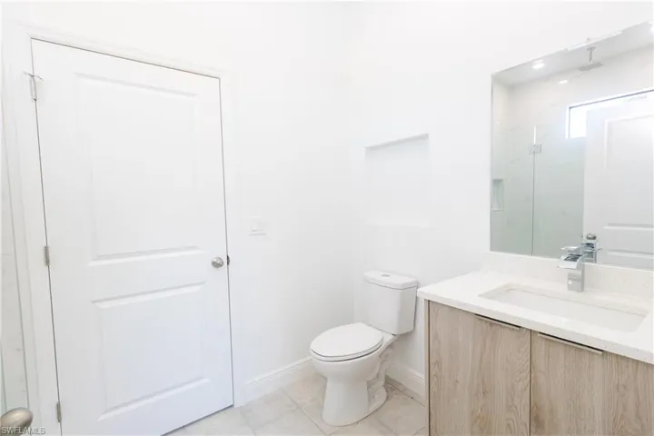 Full bathroom with vanity, a marble finish shower, and light tile patterned floors