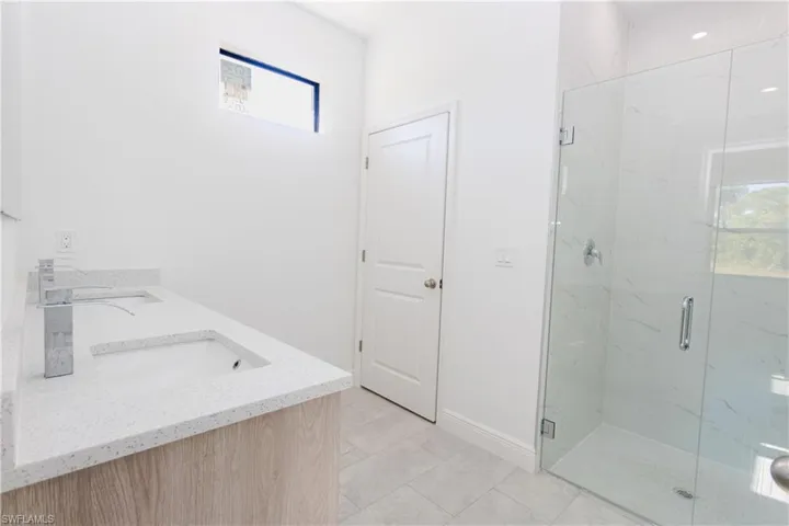 Full bath featuring double vanity and a marble finish shower