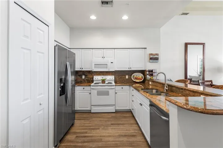 The kitchen features a combination of white and stainless steel appliances that complement the granite countertops beautifully.