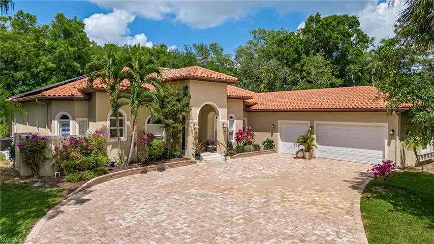 Mediterranean / spanish home with a tiled roof, an attached garage, decorative driveway, and stucco siding